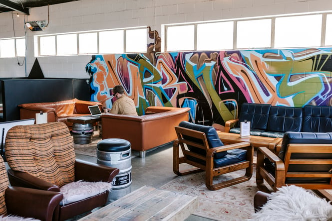 Couches placed in front of a painted graffiti wall inside an Auckland brewery.