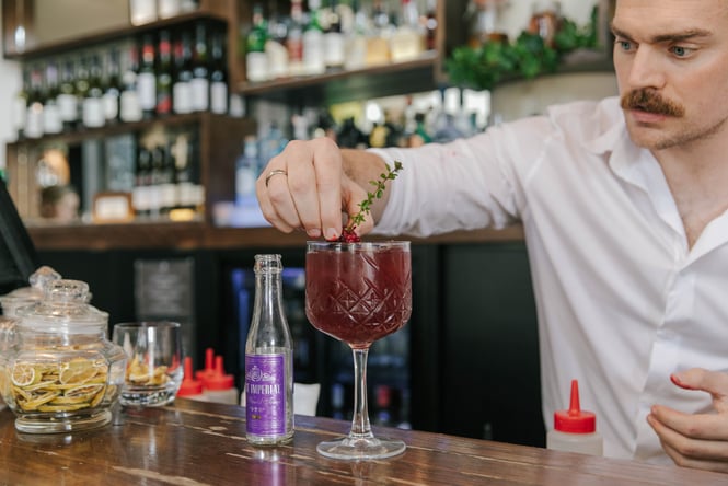 A bar man putting the final touches on a blackberry gin cocktail.