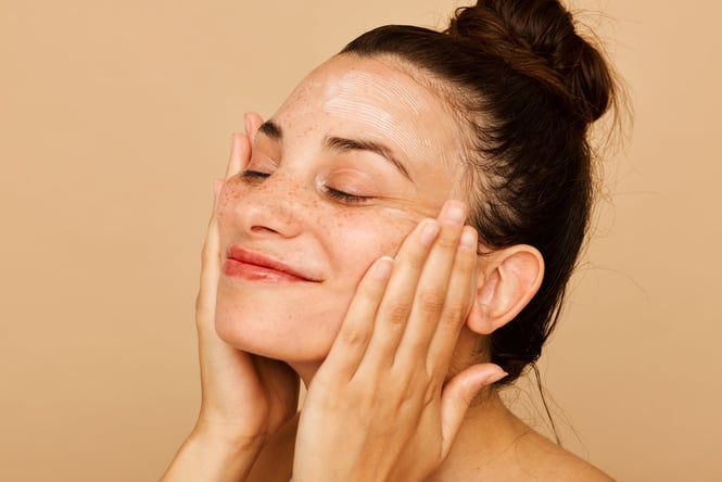 A woman with hands on her face smiling.