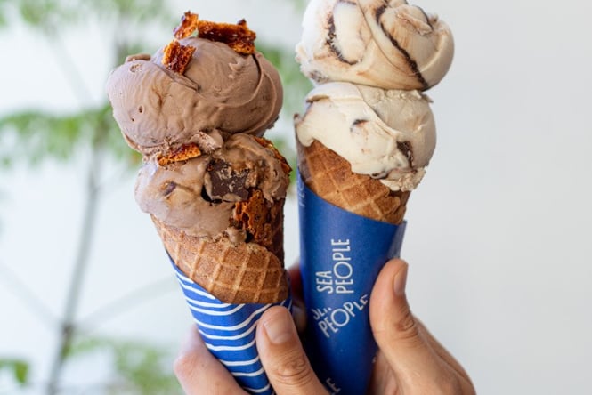 Hands holding two ice cream cones.