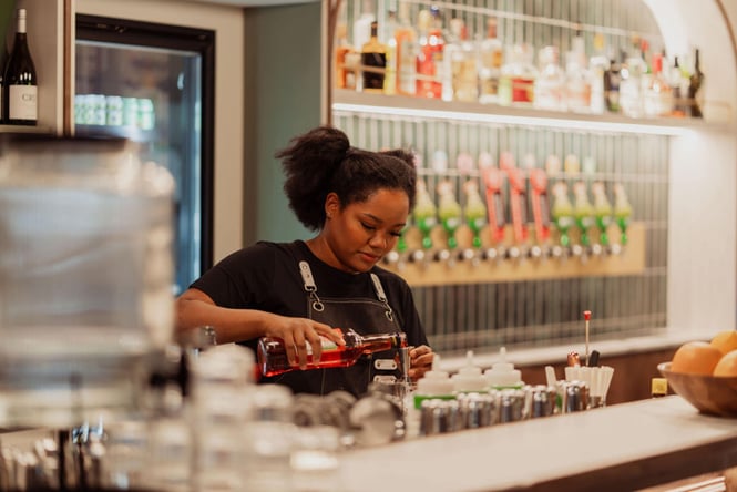 A staff member making a cocktail behind the bar at Churly's.