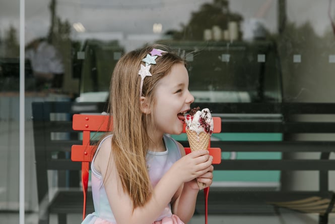 A girl eating a gelato from a cone.