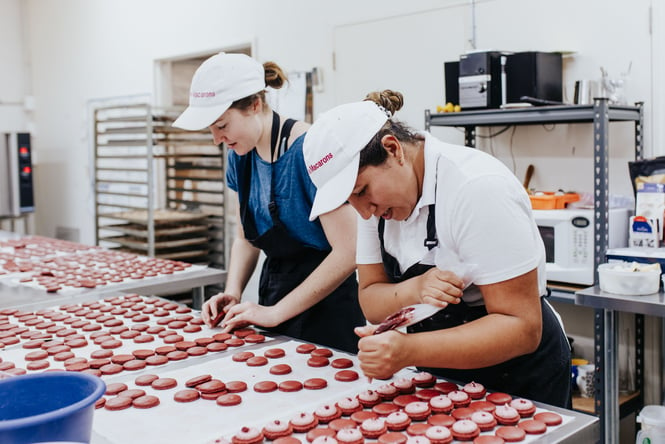 Macarons being made in a kitchen by two chefs.