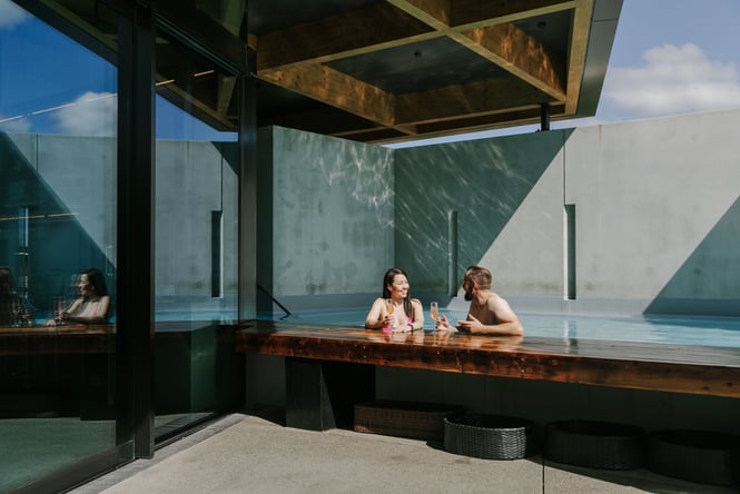 A man and woman drinking champagne at a pool bar.