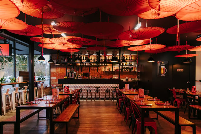 The red lit space of Formosa restaurant in Ashburton with parasols hanging from the ceiling.