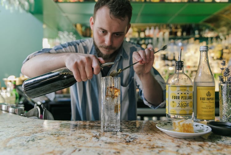 A bar man making a gin cocktail at the counter inside Gin Gin Christchurch.