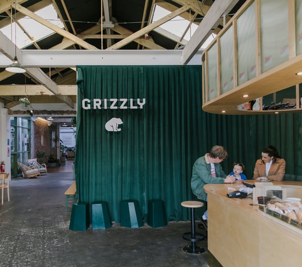 Interior view of a green velvet curtain with whit Grizzly logo.