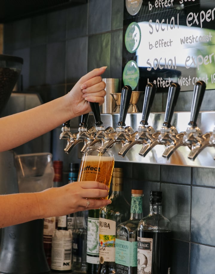 A staff member pulling a pint of craft beer behind the counter at B.Effect in Wanaka.