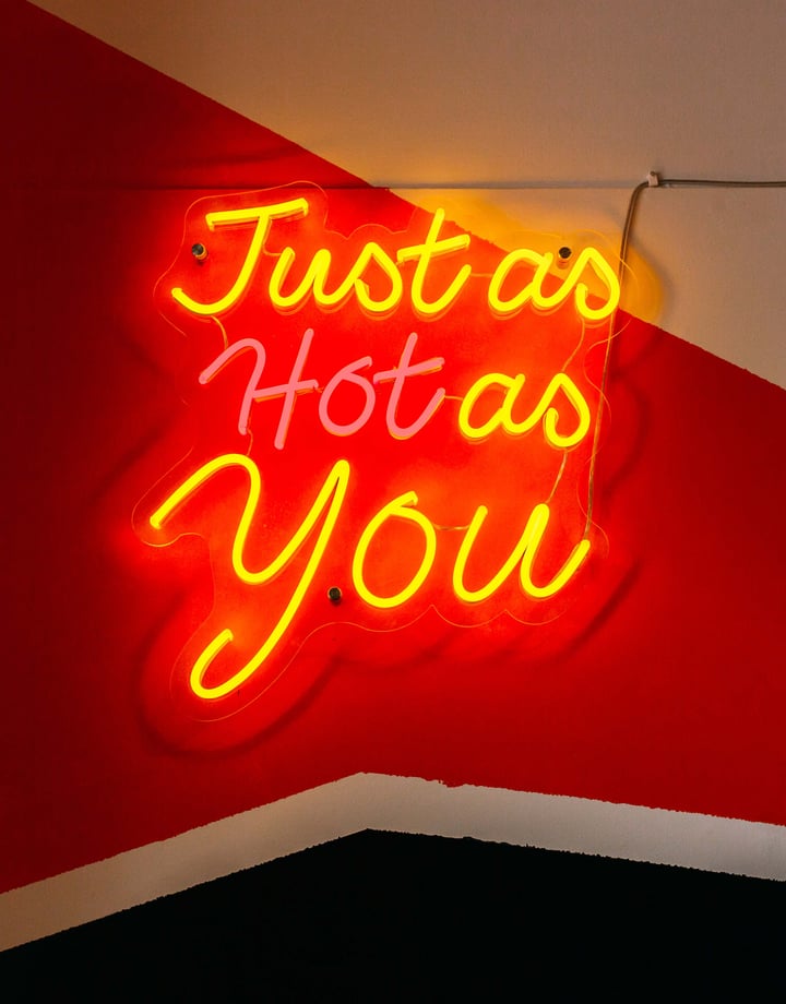 A fluorescent sign that says 'just as hot as you'.