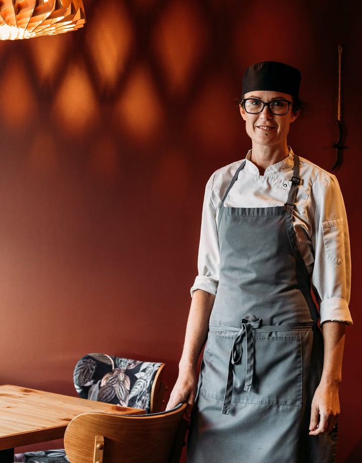A female chef in a restaurant smiling to camera.