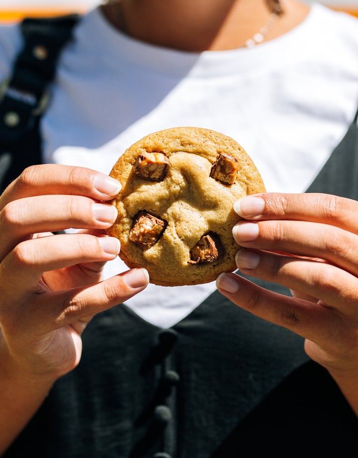 A woman holding a cookie in two hands.