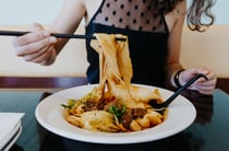 A woman eating a bowl of noodles at Miss Peppercorn in Christchurch.