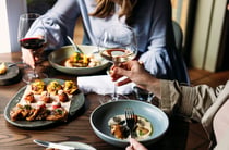 A man and woman sitting at table with beautiful plates of food.