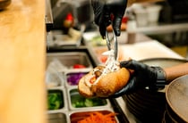 Chef filling banh mi with fresh ingredients in the kitchen