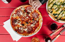 A flatly of pizza and wine on a pink table at Pipis Havelock North.