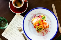 Plate of bright milk toast next to a long black coffee on cafe table