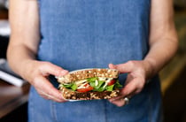 Hands holding a filled sandwich.