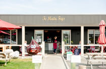 Entrance to Te Mata Figs Cafe and Shop with waiter carrying coffees out to diners sitting at outdoor tables