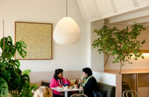 Two women talking together at a table with plates of pastries and baked goods