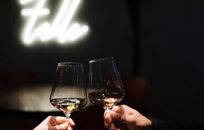 Close up of two hands clinking wine glasses.