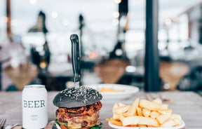 A burger, chips and beer sitting on a table in Ten27 Christchurch cafe.