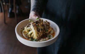 Waiter at Cucina holding a cauliflower dish.