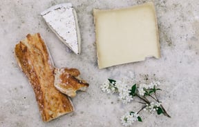 Cheese and bread on a table with flowers.