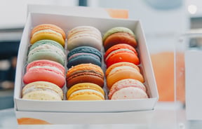 Brightly coloured macaroons in a white box.