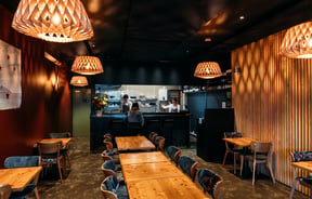 A woman sitting at the counter inside a dimly lit restaurant.