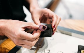 Two hands holding a beautiful pink diamond ring.