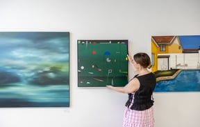 Gallery owner hangs a piece of art on the walls at Ashe.