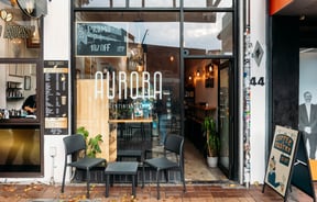 Exterior of Aurora Argentinian Bakery with signs outside.