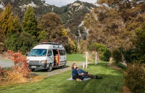 Two people sitting on grass next to a van at Awastone in Rangitikei.