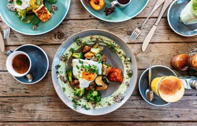 A flatlay of colourful plates of food and coffee.