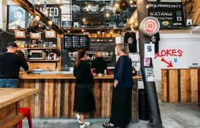 Two ladies ordering at the wood panelled counter with big festoon lights hanging above them.
