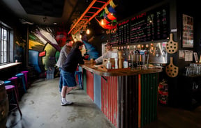 Two patrons chat with the bartender up at the bar at Brew Moon.