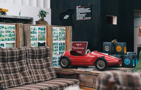 Red car by brown couch.