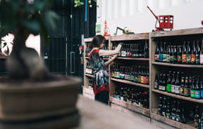 Looking at labels of the bottles on a shelf.