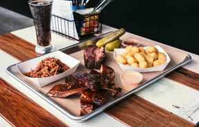 Food on a tray on a white and wooden table.