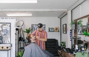 Man in the barbers seat getting a beard trim.