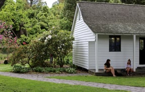 People sitting outside historic house at Christchurch Farmers Market.