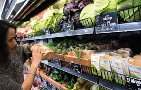 Looking at vegetables on a wooden shelf.