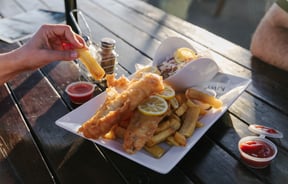 Close up of someone grabbing a chip off a plate.