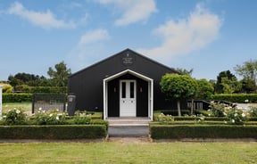 Building exterior of Country Road High Tea surrounded by gardens.