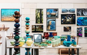 Unique sculptures and ceramics on table in front of a wall filled with artistic photography at Crafted Gallery in Ōamaru
