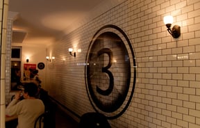 Black and white letter 3 on a white tiled wall.