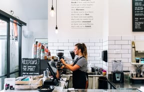 A barista making coffee behind the counter.