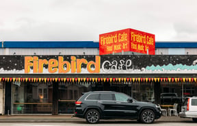 Building exterior of Firebird Cafe with a car in front on the street.
