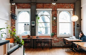 A cafe with a brick wall and large ceilings.