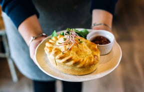 Close up of a waitress holding a pie.
